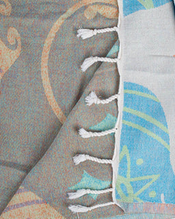 Close-up of a textured fabric with tassels and abstract patterns in gray, blue, and white.