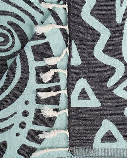 Close-up of two patterned fabrics with tassels, one in teal and black, the other in gray and white.