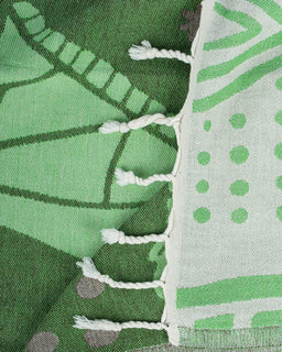 Close-up of green fabric with patterns and white fringe