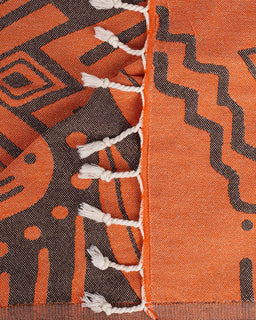 Close-up of an orange and black patterned fabric with white fringe