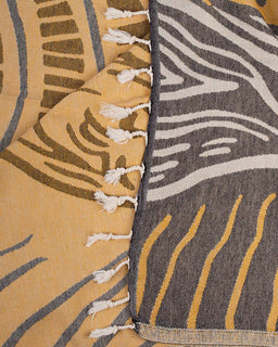 Close-up of two patterned cloths with fringe details, one in yellow and brown, the other in gray and white.