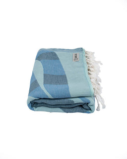 Folded blue and gray patterned towel with white tassels on a white background