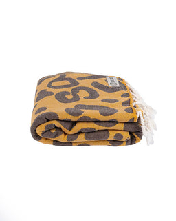 Folded towel with brown abstract pattern and white tassels on a white background