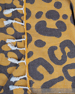 Close-up of a fabric with a leopard print pattern on a yellow and brown background.