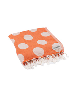 Orange towel with white polka dots and fringes on a white background