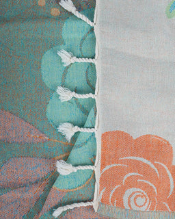 Close-up of a fabric with shell patterns and tassels on a textured background