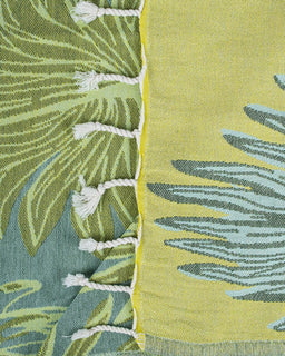 Close-up of a green and yellow fabric with leaf patterns and white tassels.