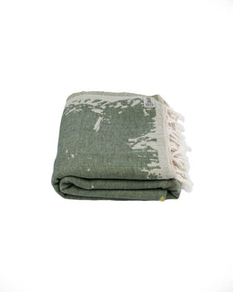 Folded green and white patterned towel with tassels on a white background