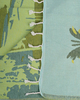 Close-up of green and blue fabric with leaf patterns and white fringe details.