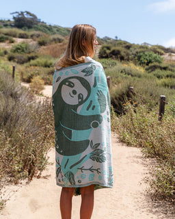 Person wrapped in a towel with a sloth design in a natural setting