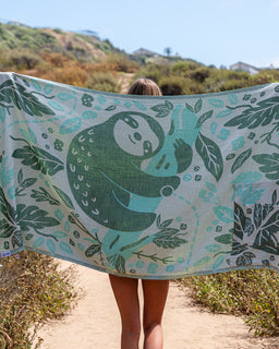 Person holding a towel with a green panda design in a natural setting