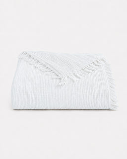 Folded white blanket with fringe tassels on white background