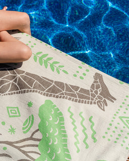 Hand holding a towel with a green and brown design over water.