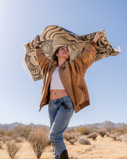 Person holding a patterned towel in a desert landscape