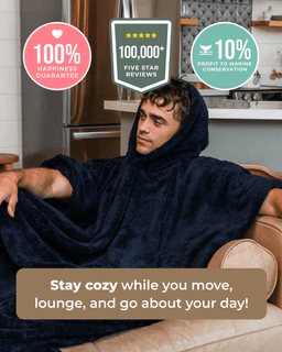 A man lounging on a couch wearing a dark navy blue hooded fleece blanket/poncho in a home setting, with promotional badges and text overlays highlighting customer reviews and benefits.