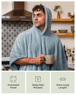 A man in a kitchen wearing a light blue oversized hooded towel wrap and holding a mug. Three feature callouts at the bottom read: Oversized Hood, Deep Side Pockets, and Extra Long Length.